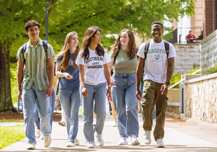 Image of five students walking together on a sidewalk.